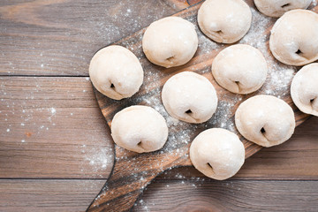 Raw dumplings ready for cooking lie in rows on a wooden cutting board on the table. Top view. Close-up