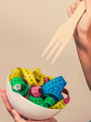 Diet. human hand and measuring tapes in bowl