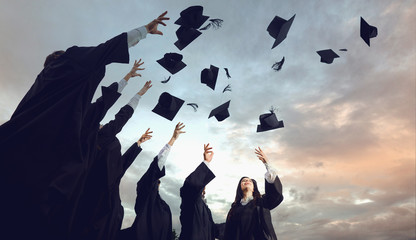 A group of graduates throws hats up into the sky.