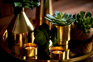 Cozy decor. Gold , burning candles Golden vessels succulents