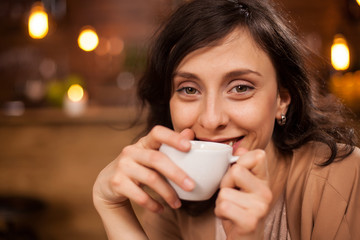 Young attractive woman smiling to camera in coffee shop