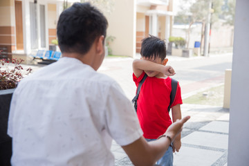 Angry father scolding son in front of the house