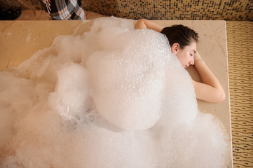 top view of a young woman in white foam relaxing in a hamam
