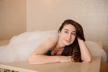 close up photo of a young woman in white foam relaxing in a hamam