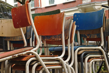 Some old weathered chairs stacked and left on the street