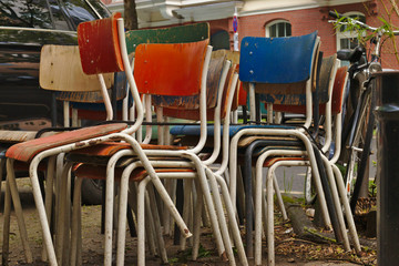 Some old weathered chairs stacked and left on the street