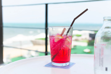 A glass of water with red drink on white table With blurred background