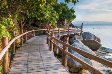 Scenic sea coastline of the Phangan island in Thailand with wooden path along the rocky shore