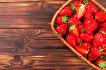 Juicy washed strawberries in wooden bowl on kitchen table.