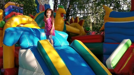 Child jumping on colorful playground trampoline. Kids jump in inflatable bounce castle on kindergarten birthday party Activity and play center for young child. Little girl playing outdoors in summer