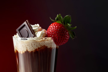 Chocolate drink with whipped cream, strawberry and pieces of black chocolate.