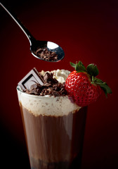 Chocolate drink with whipped cream, strawberry and pieces of black chocolate.