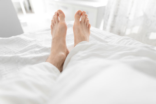 1st person view, barefoot male legs in a morning bed