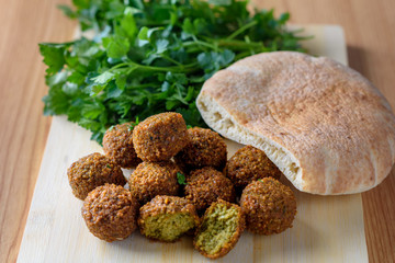 Falafel balls, pita and green fresh parsley  on wood rustic background. Falafel is a traditional Middle Eastern food, commonly served in a pitta. 