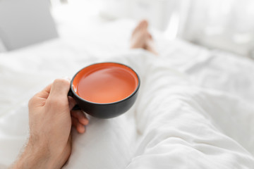 POV, man drinking morning tea in a bed