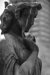 A weathered statue of a thoughtful angel on a cemetery in Toronto-Canada.
