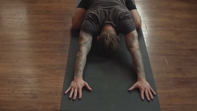 Close-up of Young man doing yoga in studio with wooden floor. Freedom, health and yoga concept.