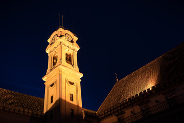 Naklejka premium Tower of Coimbra university with artificial lighting at dusk with dark sky in background.