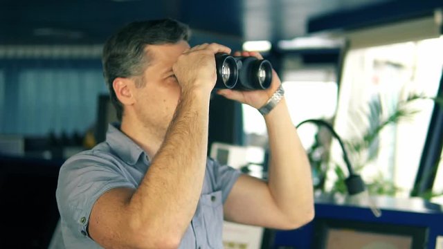 Navigational officer lookout on navigation watch looking through binoculars. Marine industry. COLREG collision regulations