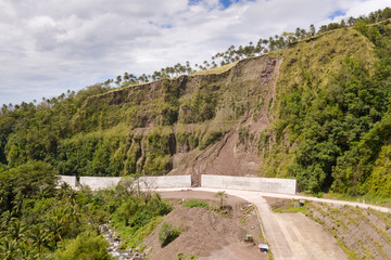 Fototapeta na wymiar Road with concrete fences on Camiguin Island, Philippines. Protection of the road from rockfalls and landslides. The collapse of the soil on the road in the highlands.