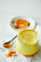 Healthy ayurvedic drink golden almond milk or pumpkin turmeric latte with curcuma powder on white background copy space.Trendy Asian natural detox beverage with spices for vegans.Alternative medicine