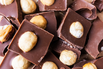 Slices of milk chocolate with hazelnuts close-up. Photo in warm colors. Sweetness. World chocolate day