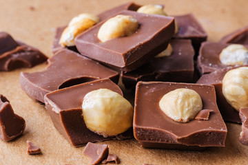 Slices of milk chocolate with hazelnuts close-up. Photo in warm colors. Sweetness. World chocolate day