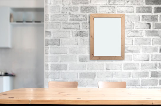 Wooden table top with white brick wall and picture frame background. Copy space for porduct display or montage.