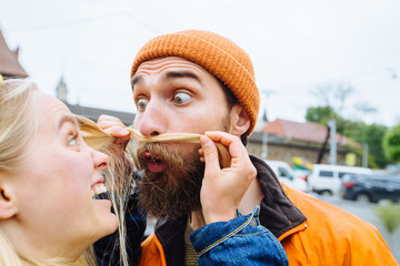 Young beautiful loving couple, a blonde woman together with her beautiful bearded man, crazy emotions, hipsters. Fun and creative, outdoor portrait, close up