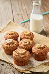Banana muffin, side view, vertical, copy space. Cupcakes on old linen napkin, rustic wooden table, breakfast with cake and milk