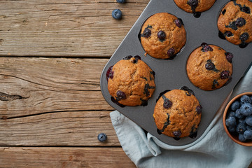 Blueberry muffin in tray, copy space. Cupcakes with berries in baking dish on old linen napkin, rustic wooden table, a breakfast with cake