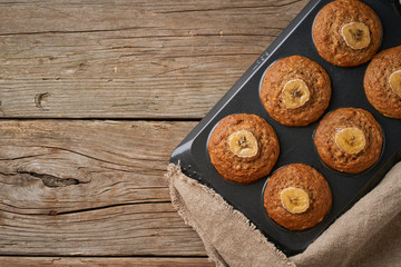 Fototapeta na wymiar Banana muffin in tray, top view, copy space. Cupcakes on old linen napkin, rustic wooden table, breakfast with cake