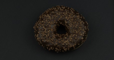 Sweet donut on black background. Top view. Tasty, fresh sprinkled donut