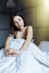 Beautiful young smiling woman sitting on bed in the morning at bedroom.