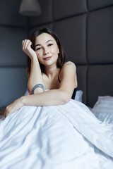 Beautiful young smiling woman sitting on bed in the morning at bedroom.