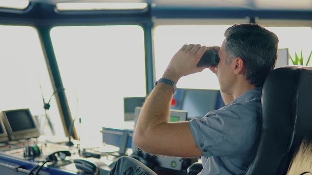 Navigational officer lookout on navigation watch looking through binoculars. Marine industry. COLREG collision regulations