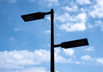 The silhouette of a lantern against the blue sky and clouds.