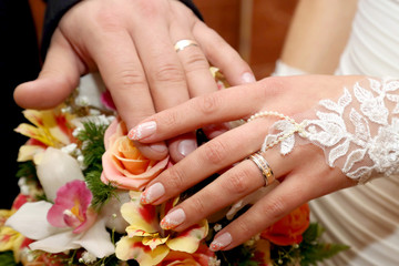 Obraz na płótnie Canvas hands of the groom and the bride on background of wedding bouquet