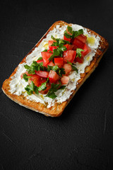 wholegraine ciabatta sandwich with sliced tomatoes, goat cheese, parsley. top view
