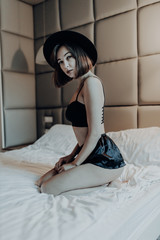 Young beautiful girl in black hat in bed at home