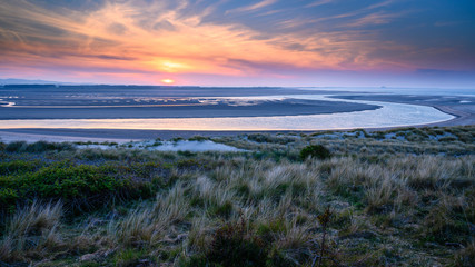 Sunset at Budle Bay, the mud flats at low tide are part of Lindisfarne Nature reserve on...