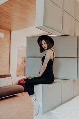 Pretty woman with black hat sitting at home in the living room