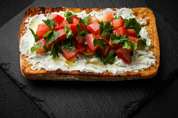 wholegraine ciabatta sandwich with sliced tomatoes, goat cheese, parsley. top view