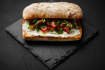 wholegraine ciabatta sandwich with sliced tomatoes, goat cheese, parsley. top view