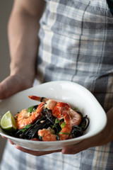 Black pasta with king prawns in a deep plate