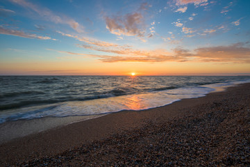 Fototapeta premium gorgeous sunset on the sea coast. photo on long exposure, waves at sea at sunset. pink sunset