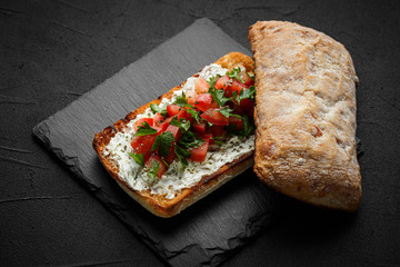 wholegraine ciabatta sandwich with sliced tomatoes, goat cheese, parsley. top view