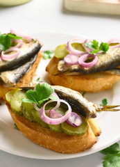 Sandwiches with sprats, marinated cucumber and onion
