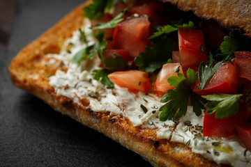 wholegraine ciabatta sandwich with sliced tomatoes, goat cheese, parsley. top view