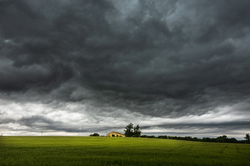 Fototapeta na wymiar Threatening sky over a farm house in springtime